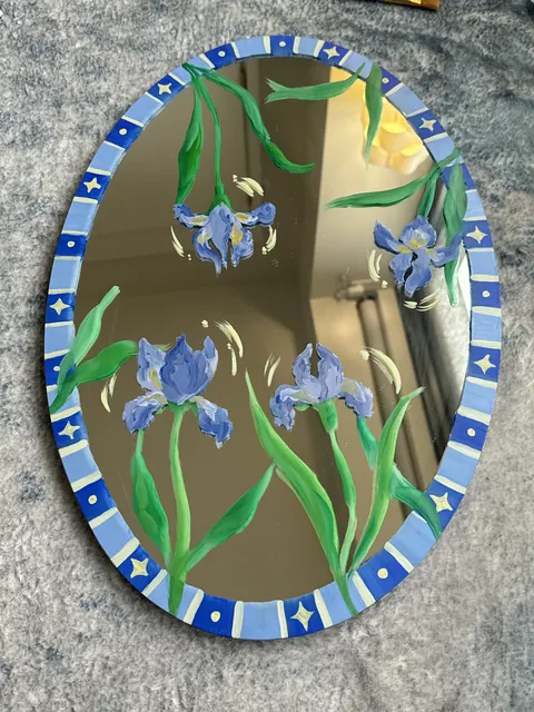 An oval mirror painted with blue irises