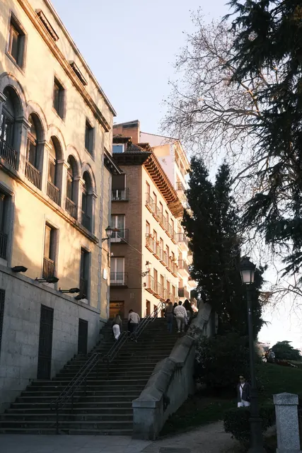 A stone staircase climbing between old buildings and trees