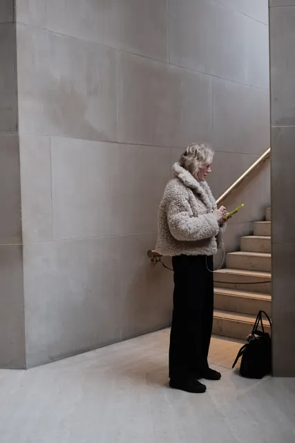 A woman in a fur coat on a pale stone staircase