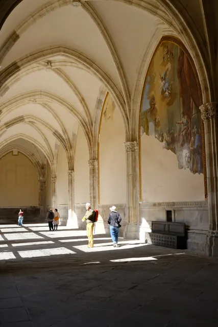 A sunlit cloister with frescoes and vaulted arches